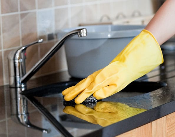 rubber gloved hand wiping down a counter with a sponge