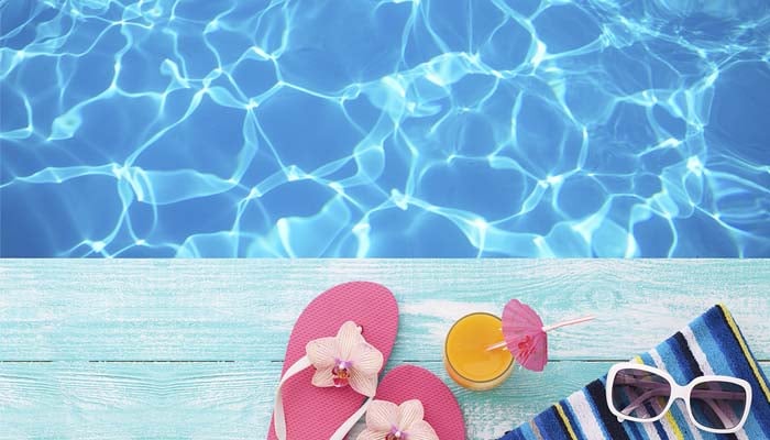 sunbathing items and a drink sitting next to a pool